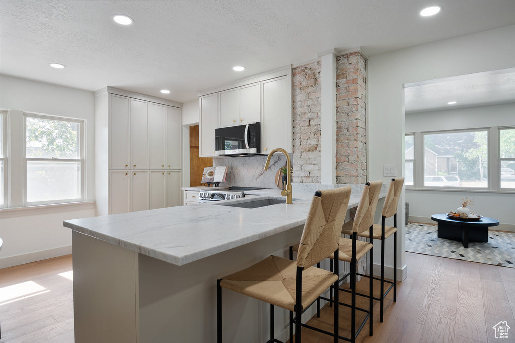 Kitchen with stainless steel microwave, light stone counters, healthy amount of natural light, recessed lighting, and light wood finished floors