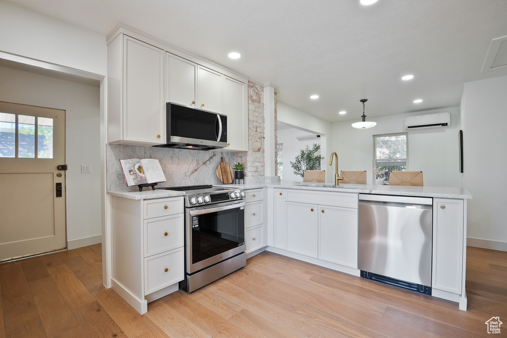 Kitchen featuring stainless steel appliances, a wall mounted AC, plenty of natural light, light wood finished floors, and recessed lighting