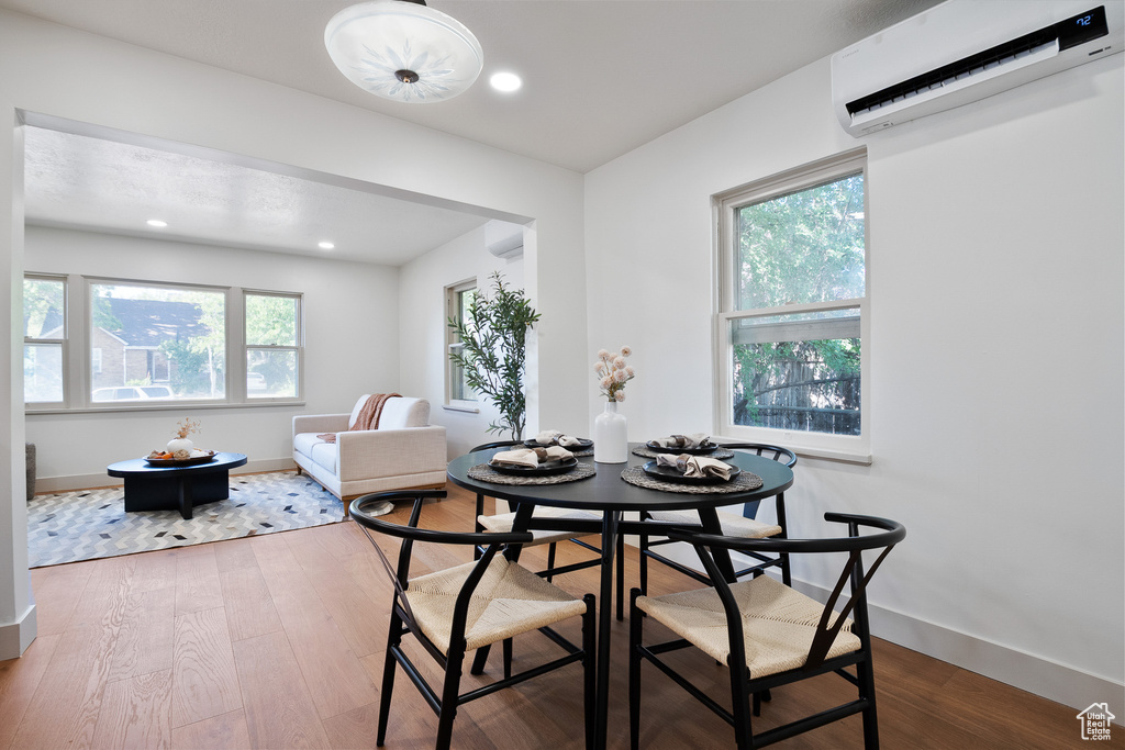 Dining area featuring a wall unit AC, wood finished floors, and recessed lighting