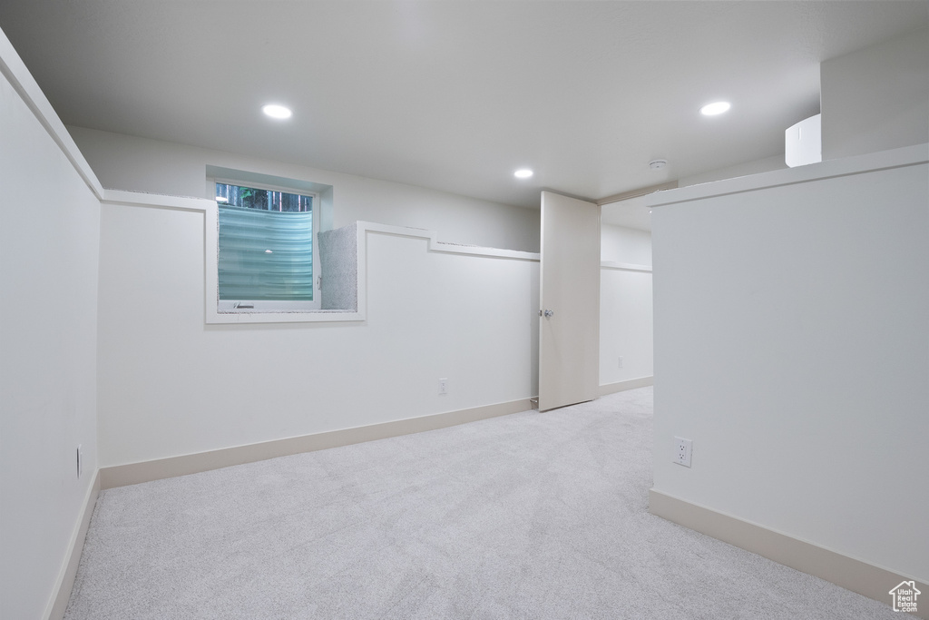Finished basement with light colored carpet and recessed lighting