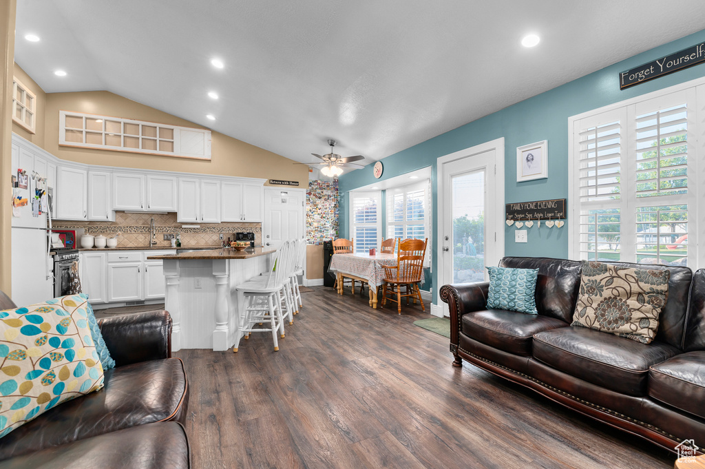 Living room featuring a ceiling fan, dark wood-style floors, lofted ceiling, and recessed lighting