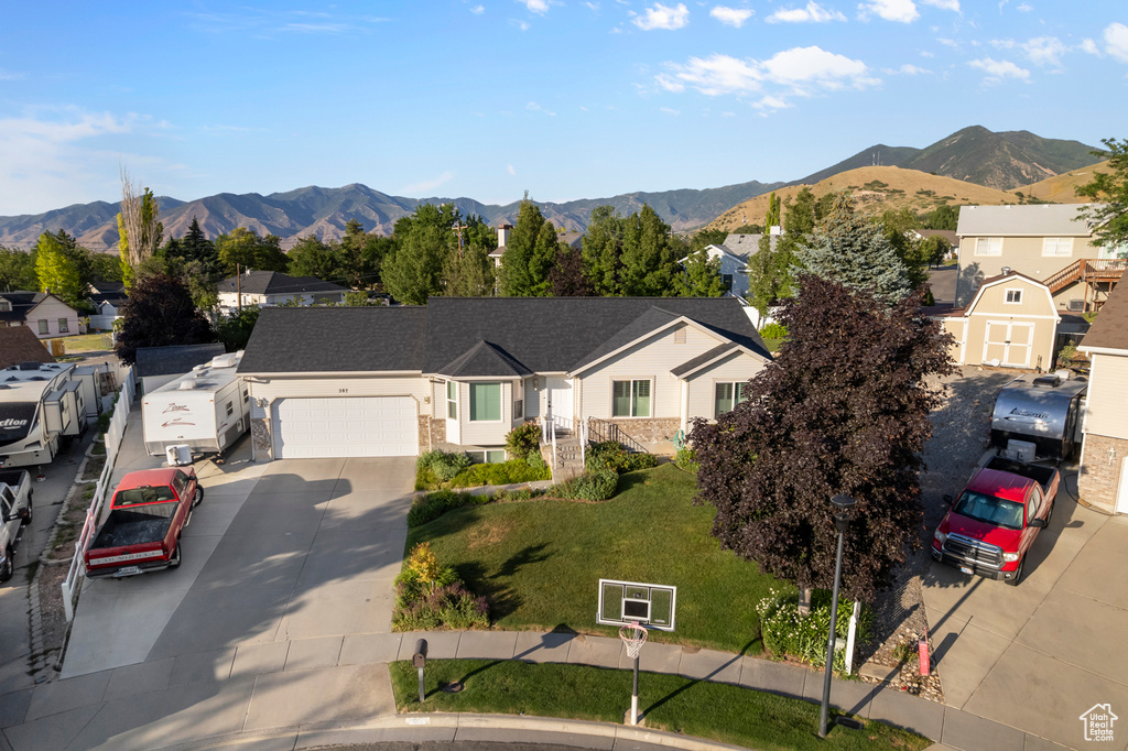 Ranch-style home with an attached garage, concrete driveway, a mountain view, and a residential view