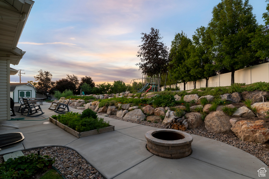 View of patio / terrace with a playground, an outdoor fire pit, and a shed