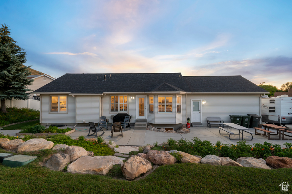 Rear view of house with entry steps, a patio area, and roof with shingles
