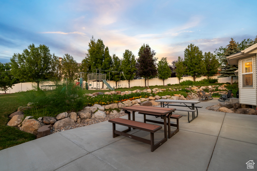 Fenced backyard with a patio area, a playground, and outdoor dining space