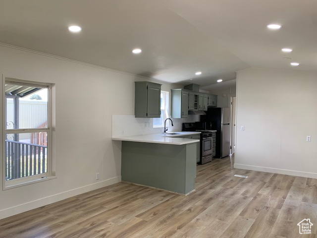Kitchen featuring appliances with stainless steel finishes, light countertops, plenty of natural light, a peninsula, and ornamental molding