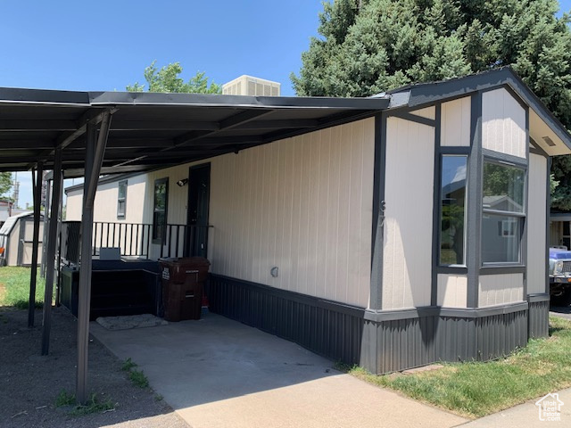 View of front of house with an attached carport, a shed, and driveway