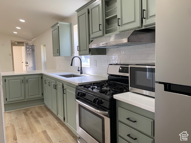 Kitchen with freestanding refrigerator, stainless steel range with gas stovetop, green cabinets, a peninsula, and decorative backsplash