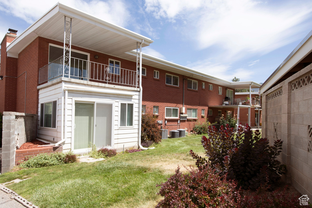 Back of property with a balcony, a lawn, and a chimney