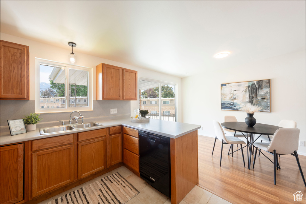 Kitchen featuring black dishwasher, a peninsula, light countertops, and brown cabinetry