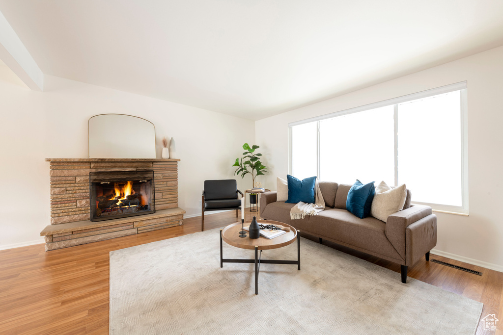 Living area with light wood-style flooring and a stone fireplace