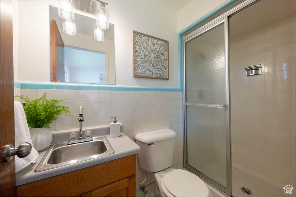 Full bathroom featuring vanity, a stall shower, tile walls, and wainscoting