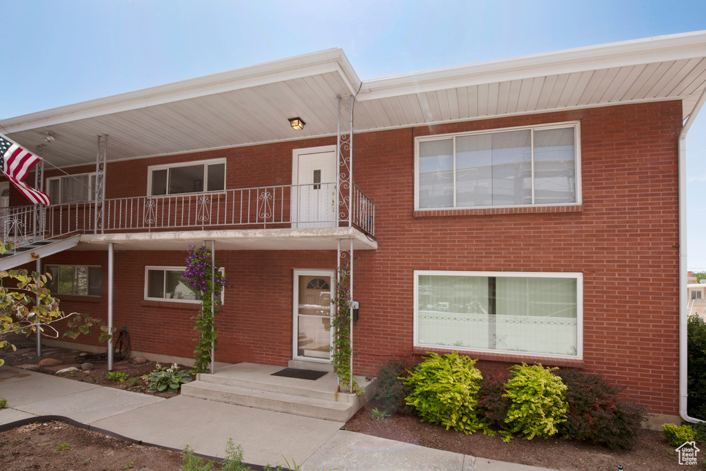 View of front of property featuring a balcony and brick siding