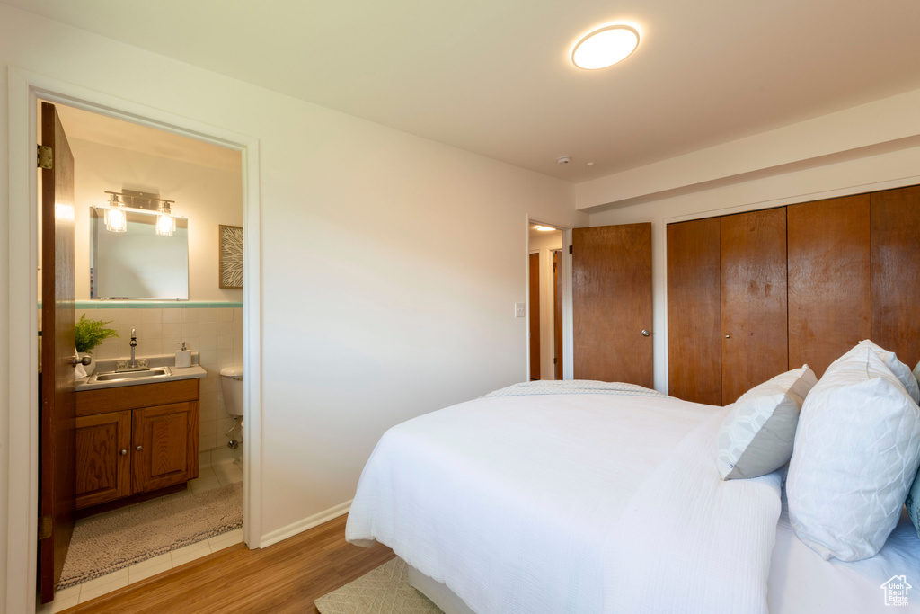 Bedroom with light wood-style floors and connected bathroom