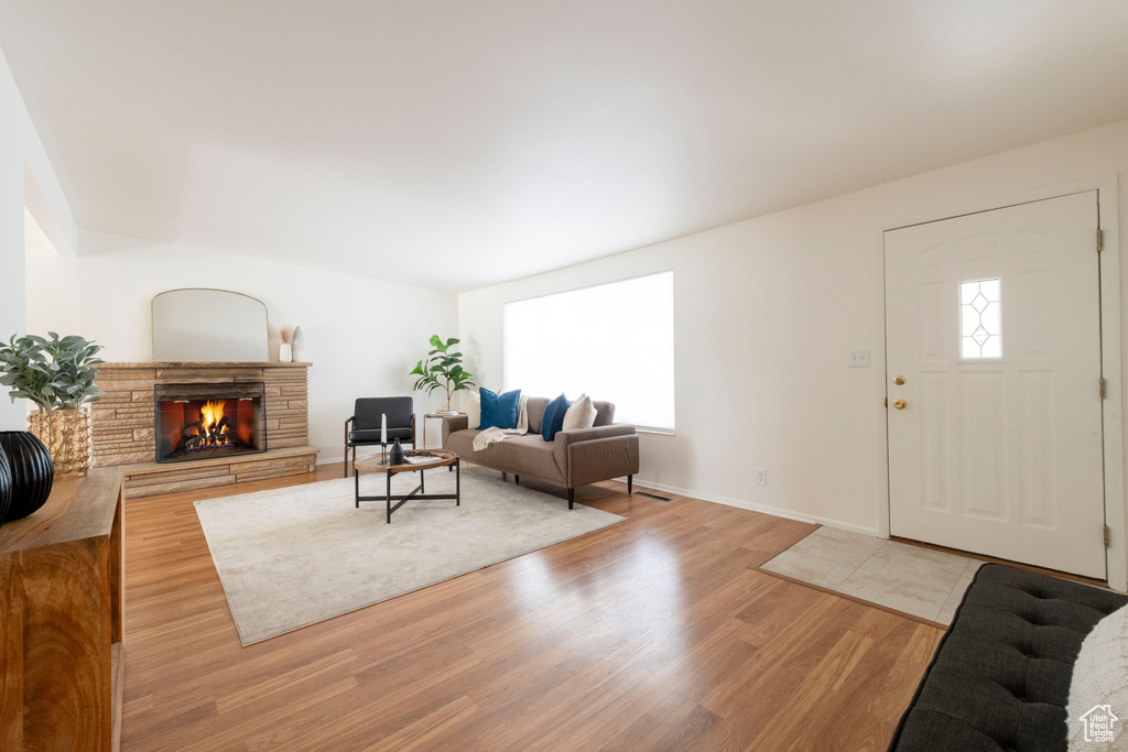 Living area with healthy amount of natural light, light wood finished floors, and a stone fireplace