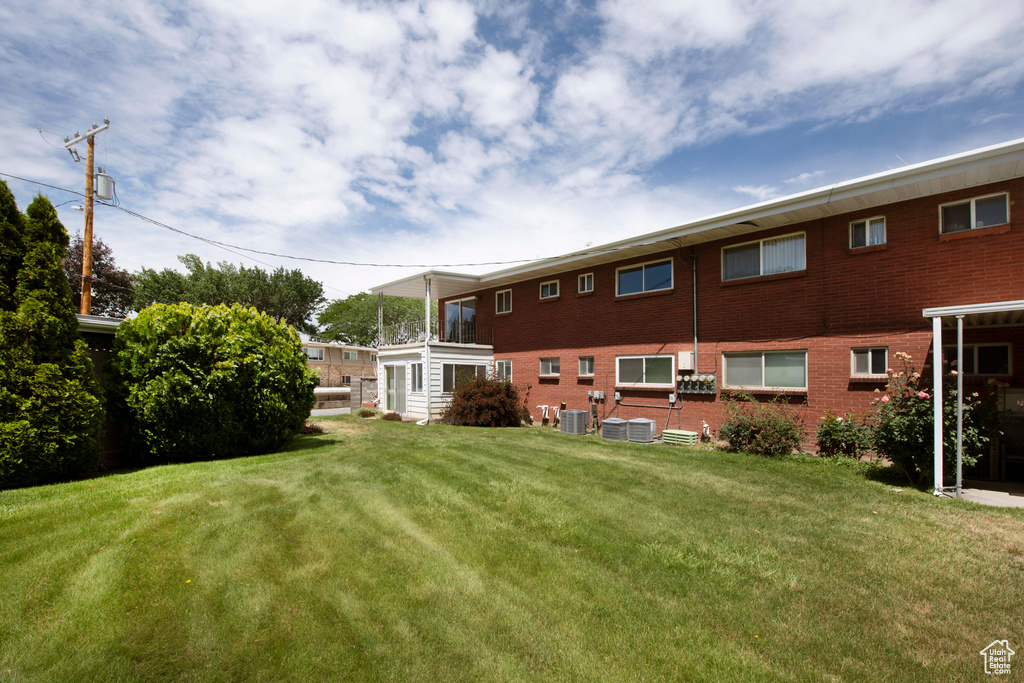 Back of house featuring a lawn and brick siding