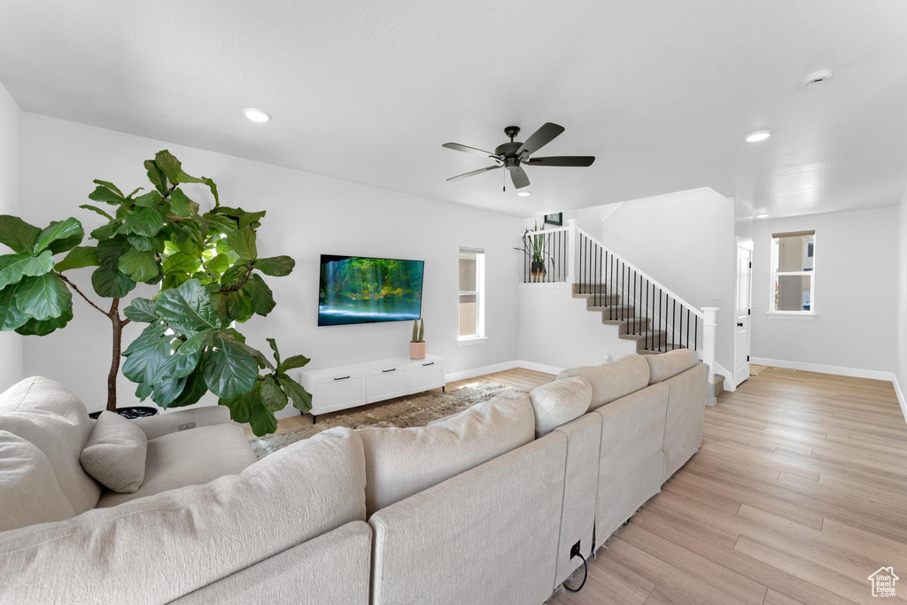 Living area with stairway, recessed lighting, a ceiling fan, and light wood-type flooring