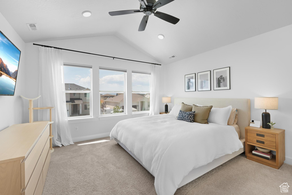 Bedroom with vaulted ceiling, light carpet, and a ceiling fan