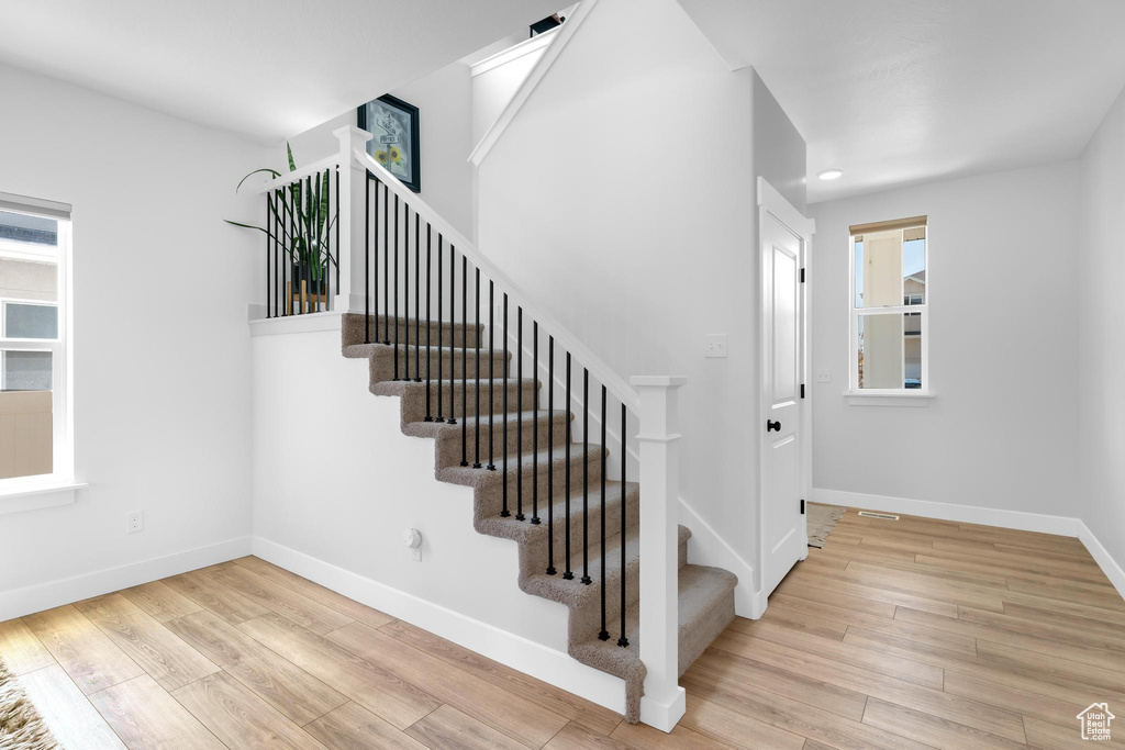 Stairs with wood finished floors and recessed lighting