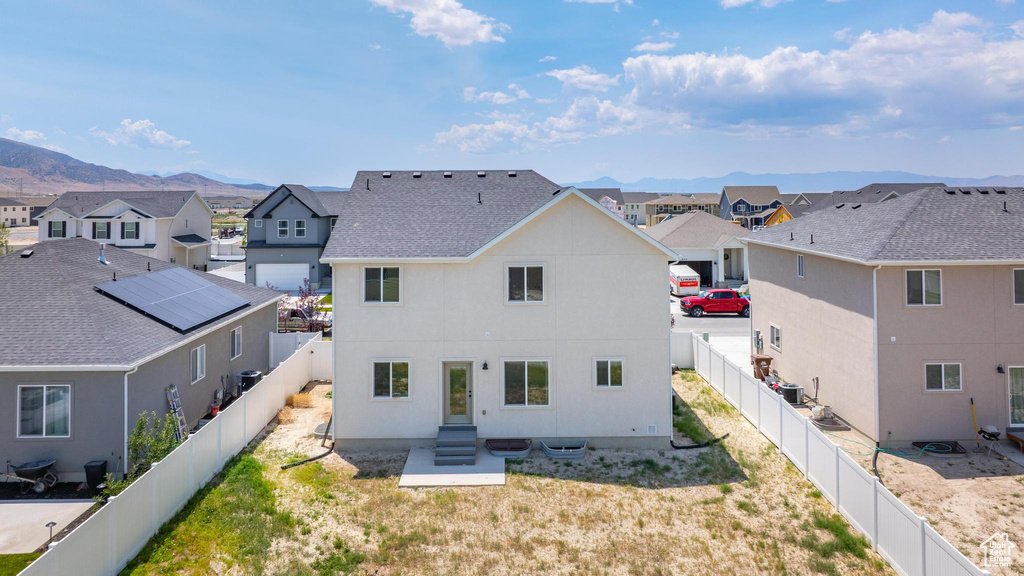 Rear view of property with a residential view, a mountain view, roof with shingles, stucco siding, and a fenced backyard