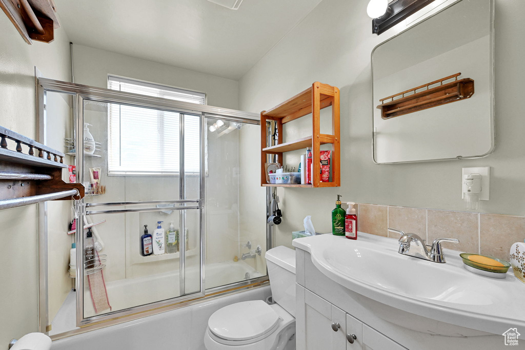 Bathroom with vanity, combined bath / shower with glass door, and backsplash