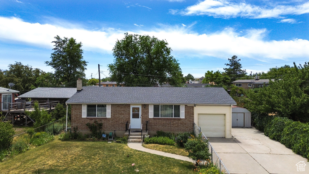 Ranch-style home with driveway, a storage shed, brick siding, an attached garage, and a chimney