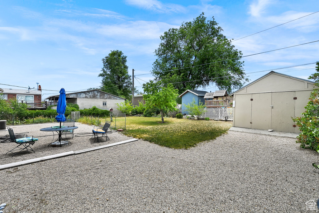 View of grassy yard featuring a patio area and a storage unit