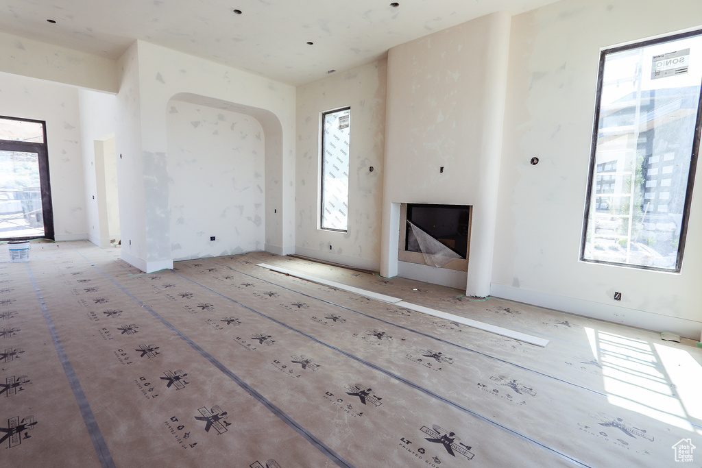 Unfurnished living room featuring arched walkways and a fireplace