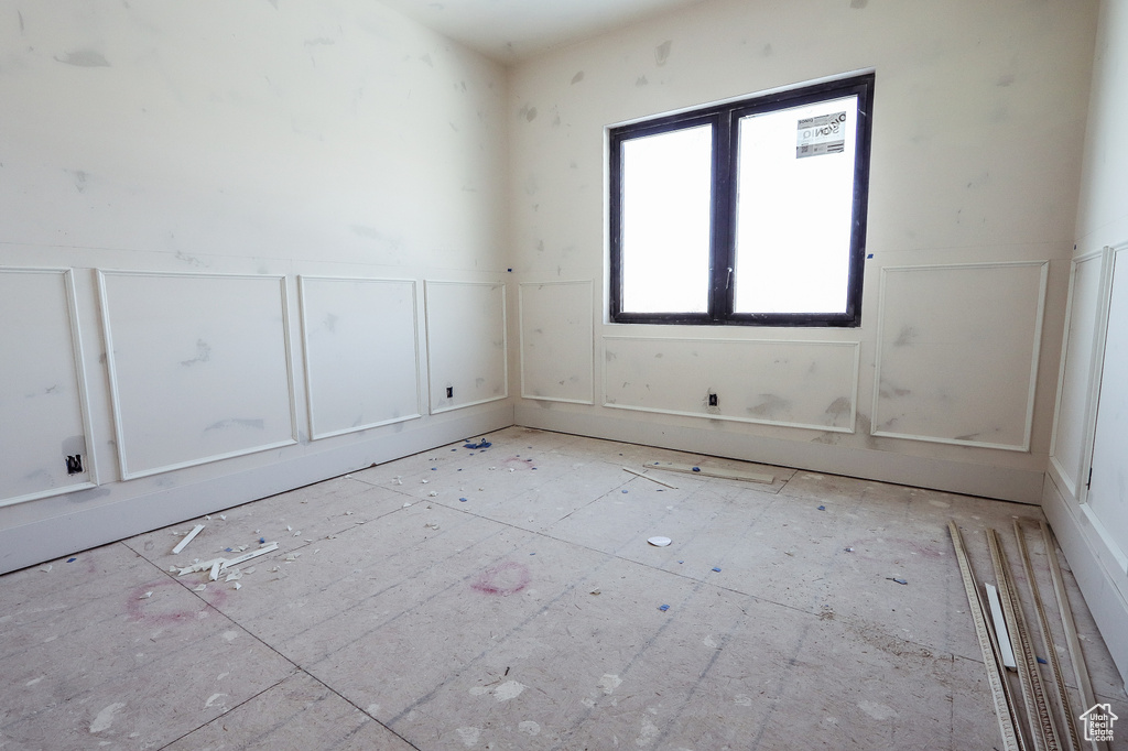 Empty room featuring a decorative wall and wainscoting