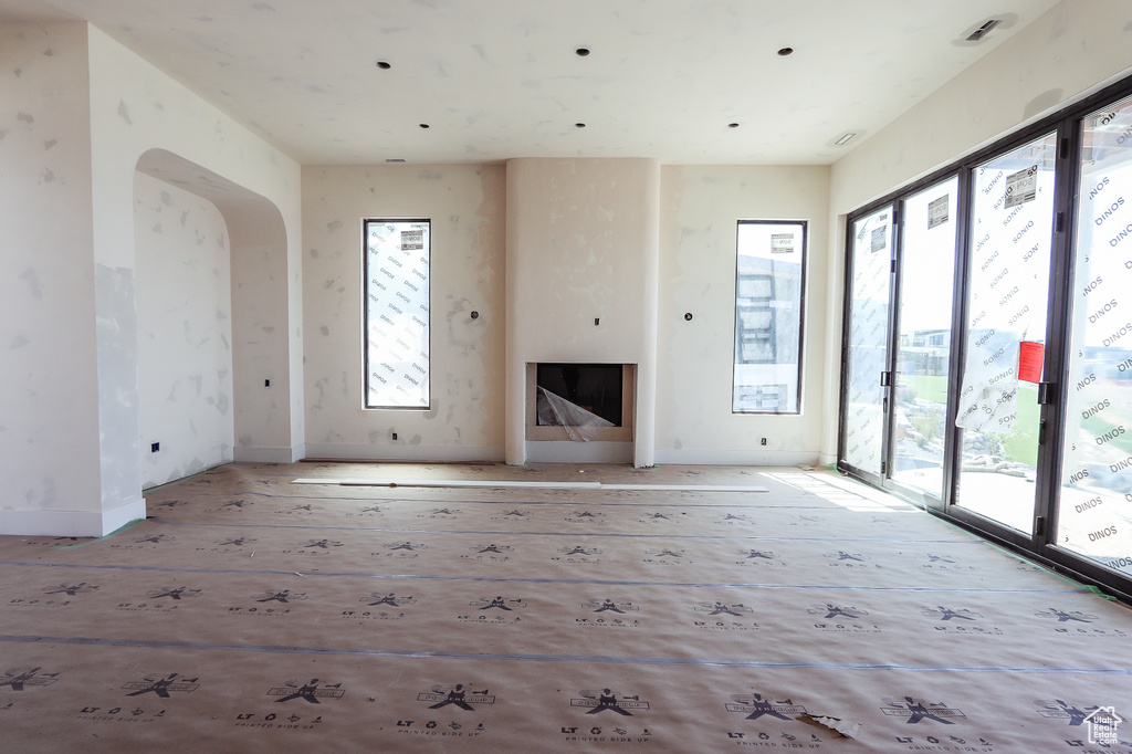 Unfurnished living room with arched walkways, wood finished floors, and a fireplace