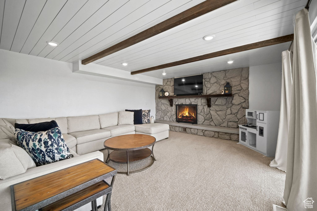 Living room with carpet floors, beam ceiling, a stone fireplace, and recessed lighting