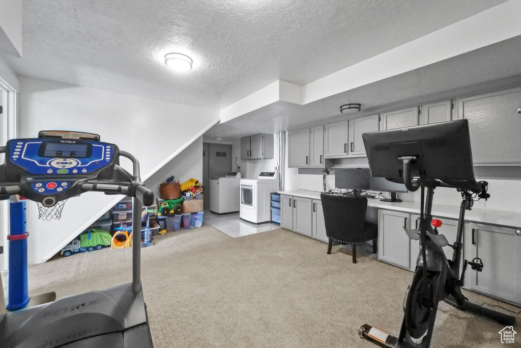 Exercise area featuring light colored carpet, a textured ceiling, and washer and clothes dryer