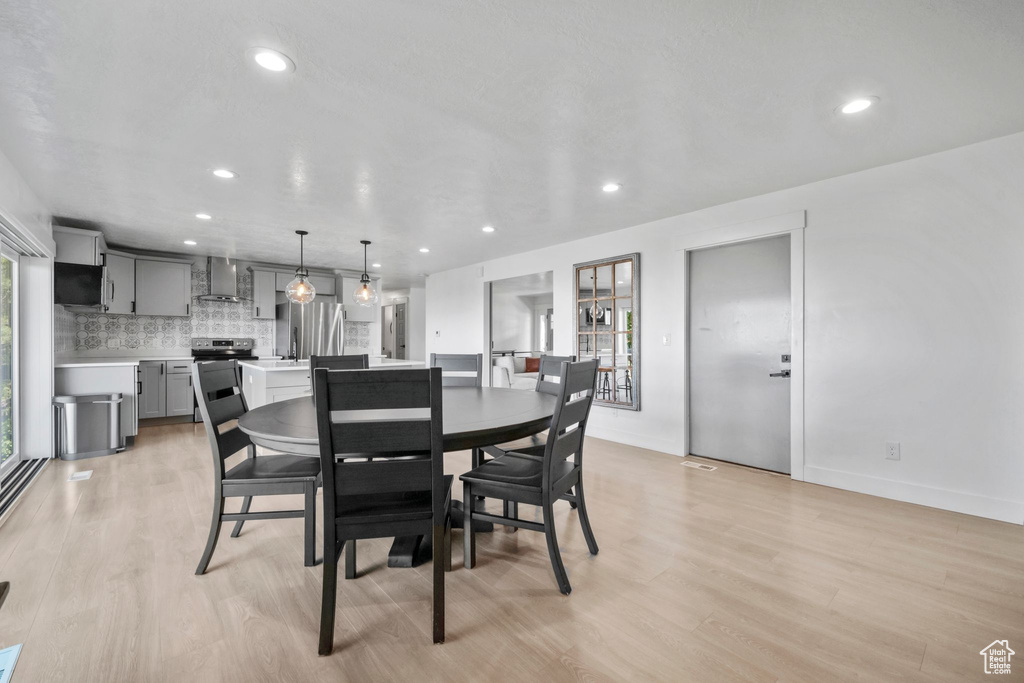Dining room with light wood-type flooring and recessed lighting