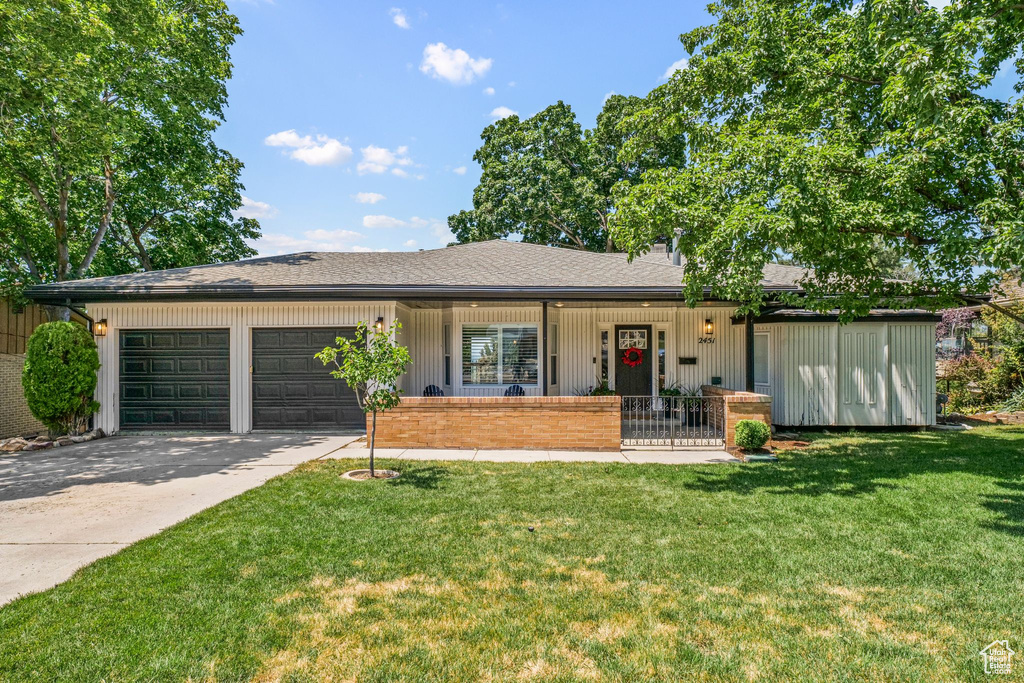 Ranch-style home featuring a porch, a garage, driveway, a front lawn, and a shingled roof