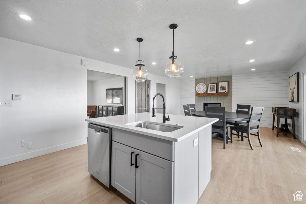 Kitchen with stainless steel dishwasher, recessed lighting, light wood-type flooring, a center island with sink, and light countertops