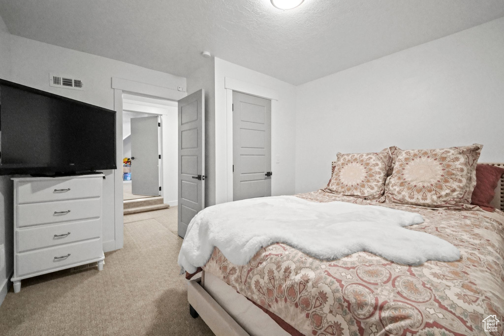 Bedroom with light carpet and a textured ceiling
