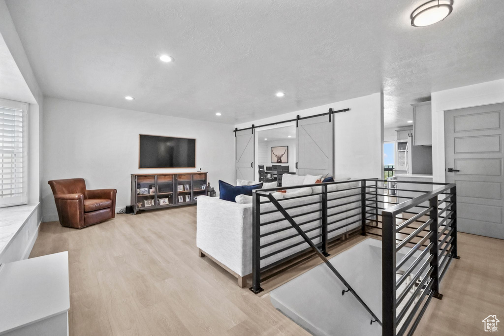 Living area with a barn door, wood finished floors, and recessed lighting