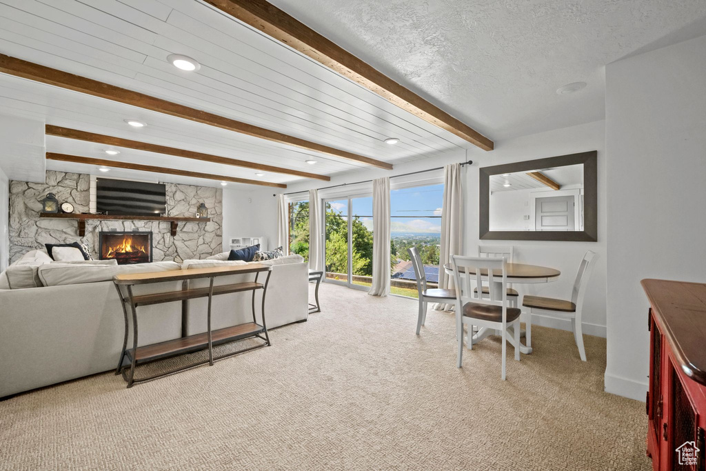 Living area with beam ceiling, light colored carpet, a fireplace, recessed lighting, and a textured ceiling