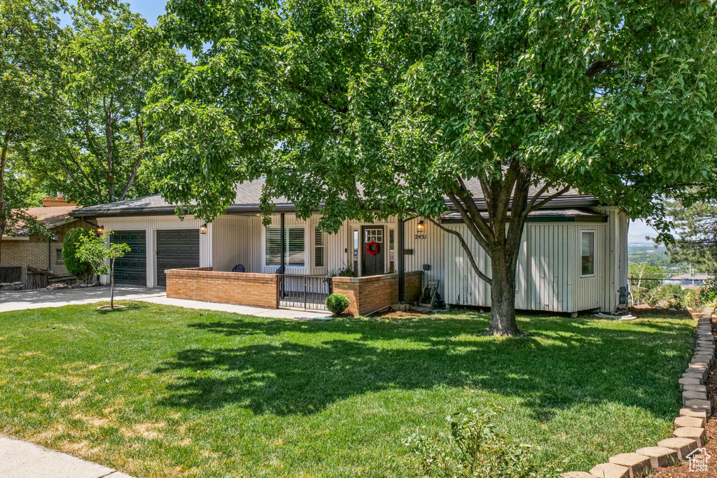 View of property hidden behind natural elements featuring a garage and concrete driveway