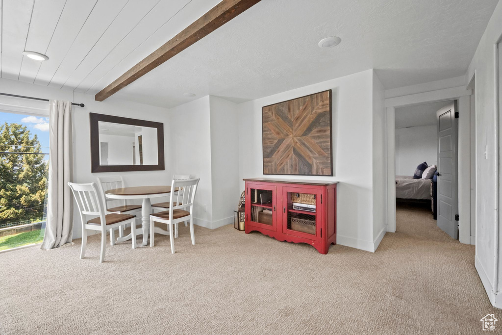 Carpeted dining space featuring beamed ceiling and baseboards