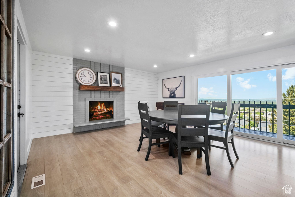 Dining room with a large fireplace, wood finished floors, recessed lighting, and a textured ceiling