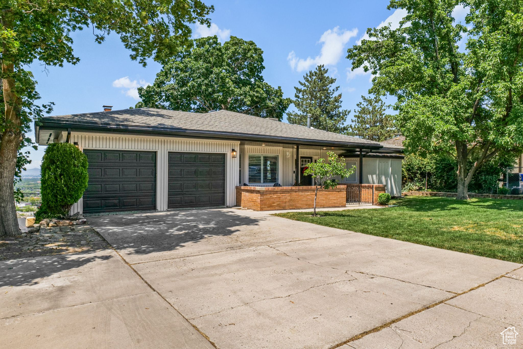 View of front of home featuring a garage, a front lawn, driveway, brick siding, and a porch