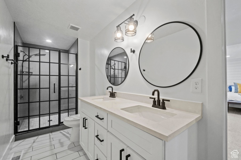 Full bath featuring double vanity, a stall shower, and ensuite bathroom
