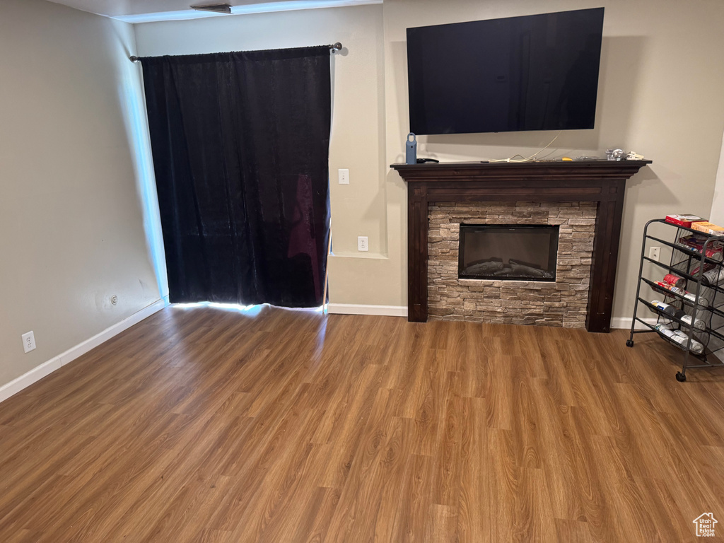 Unfurnished living room featuring a stone fireplace and wood finished floors