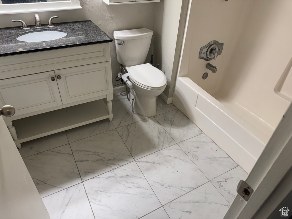 Full bath with marble look tiles, vanity, and shower / bath combination