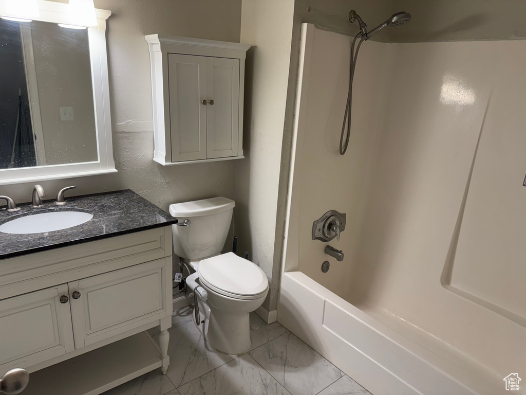 Bathroom featuring vanity, marble finish flooring, and washtub / shower combination