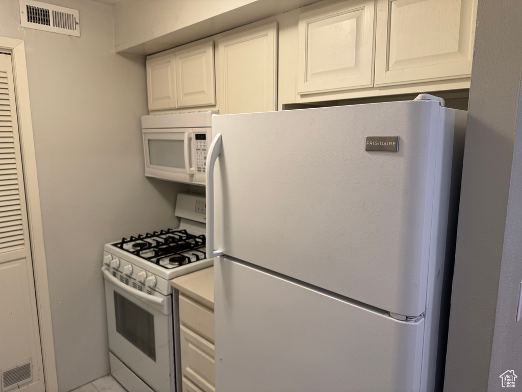 Kitchen with white appliances, light countertops, and white cabinetry