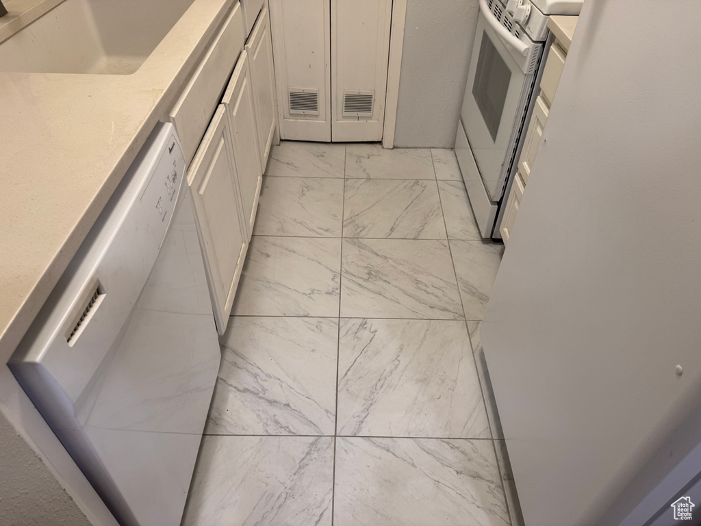 Kitchen with white appliances, light marble finish flooring, white cabinets, and light stone countertops