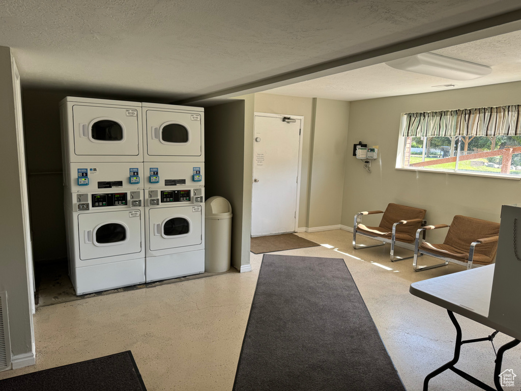 Shared laundry room featuring stacked washer / dryer and baseboards