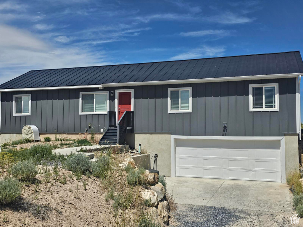 Ranch-style home featuring a metal roof, an attached garage, concrete driveway, and board and batten siding